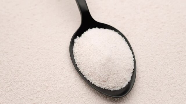 collagen powder in spoon on collagen powder on background. top view