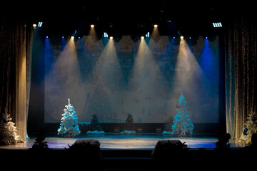 Theater before the performance of artists. Bright colored light and scene with Christmas trees.