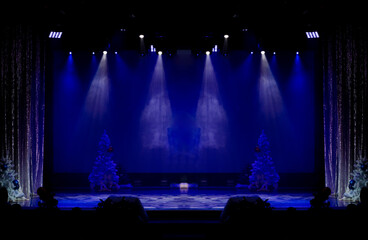 Theater before the performance of artists. Bright colored light and scene with Christmas trees.