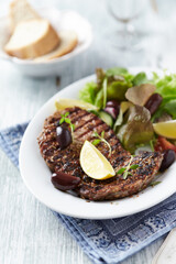 Grilled pork steak with fresh salad. Bright wooden background. Close up. 