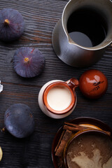coffee with natural cream and tasty ripe purple fig on black wooden table. flat lay