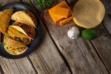 Rustic wooden table with plate of tasty mexican tacos. Cheese and corn tortillas on the wooden...