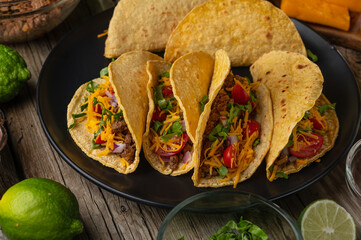Close-up view of juicy tasty tacos with beef meat and vegetables on wooden background. Preparing traditional dish mexican cuisine. Mouthwatering food concept.