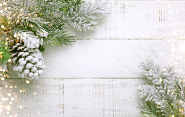 Christmas tree branch and pine cone in snow on a white wooden background. Winter festive concept....