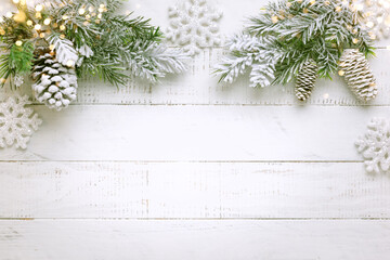 Christmas tree branch with pine cone in snow and retro style clock on a white wooden background....