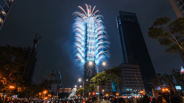 Taipei City Night landscape and Taipei 101 skyscraper is lit up by fireworks. People watching and taking photos and videos around buildings to celebrate the new year event.