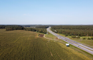 Fototapeta premium Top view of car asphalt highway with cars through fields