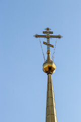 Fototapeta na wymiar Beautiful gold cross of the Christian Russian church against the blue sky. Religion and culture of Russia.