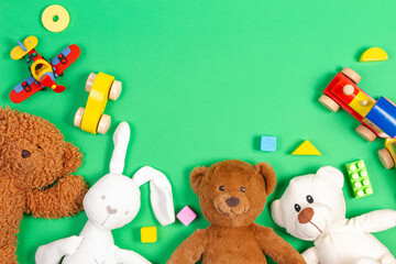 Baby kids toys background. Teddy bears, wooden train, toy cars, colorful blocks on light green background. Top view