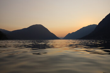 Colorful sunset in Italy over a mountain range with still lake in foreground during golden hour in late summer