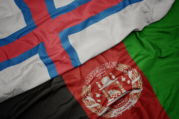 waving colorful flag of afghanistan and national flag of faroe islands. macro