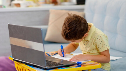 Little boy in virtual class. School at home. little cute boy is taking an online drawing lesson. the child is engaged in creativity at home © yavdat
