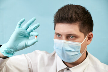 man in medical protective mask with pills on blue background