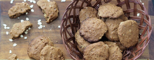 Homemade oatmeal cookies with whole grain rye flour in a plate made from natural vine on a wooden background.Diet healthy food.
