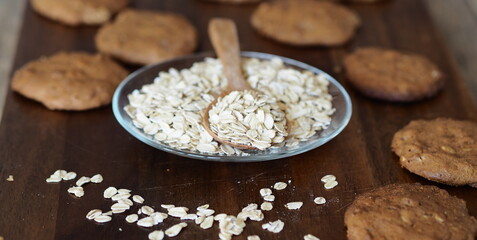 Homemade oatmeal cookies with whole grain rye flour in a glass plate with oatmeal grains on a kitchen board.Diet healthy food.