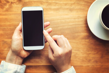 Person using a white smartphone on a wooden table
