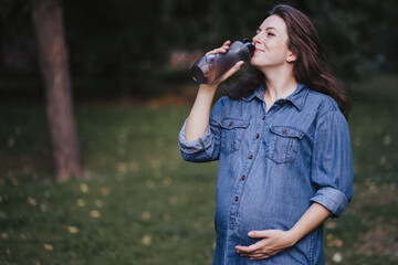 Pregnant woman drinking water during outdoor walk