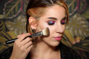 beautiful young woman putting on makeup