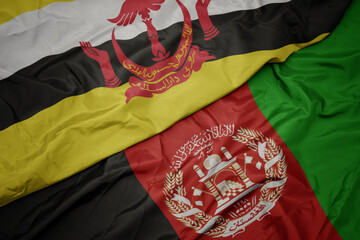 waving colorful flag of afghanistan and national flag of brunei. macro