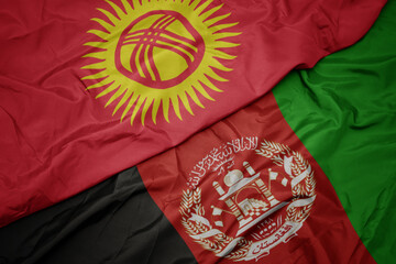 waving colorful flag of afghanistan and national flag of kyrgyzstan. macro