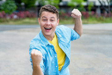 Successful cheering german young adult man outdoor in city