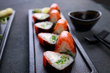 Salmon sushi rolls on black plate, selective focus
