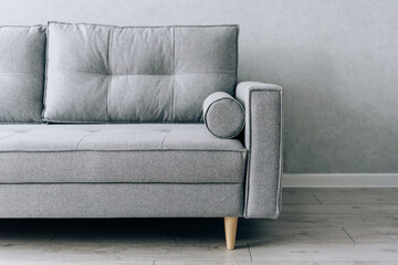 Modern grey sofa with wooden legs in the room