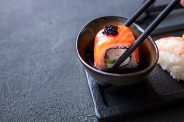 Chopsticks dipping salmon maki sushi into sauce © Vadym