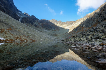 Fototapeta na wymiar Pond in Valley of Five Spis Lakes surrounded by rocky summits, High Tatra Mountains. Slovakia