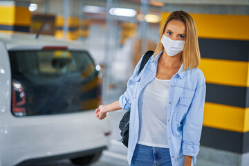 Fototapeta premium Student in mask leaving car in underground parking lot