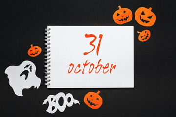 Happy halloween holiday concept. Notepad with text 31 october on black background with bats, pumpkins and ghosts