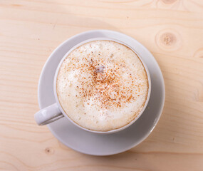 a white ceramic cup of cappucino as a coffee break concept