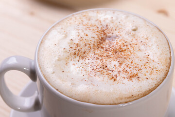 a white ceramic cup of cappucino as a coffee break concept