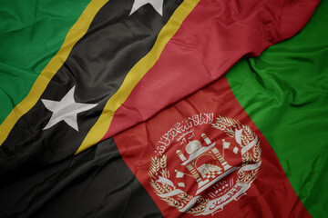 waving colorful flag of afghanistan and national flag of saint kitts and nevis. macro
