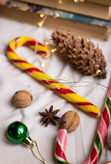 The atmosphere of Christmas and New Year. Big spruce cone, colored caramel paosokhs, Christmas balls and walnuts on a light background