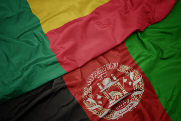 waving colorful flag of afghanistan and national flag of benin. macro