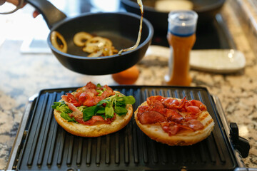 Woman cooking bacon and cheese burgers at home