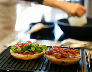 Woman cooking bacon and cheese burgers at home