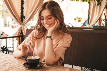 Young beautiful smiling hipster female in trendy summer clothes.Carefree woman sitting in veranda...