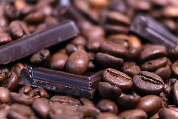 Close-up of dark roasted coffee beans and chocolate background.