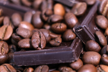 Close-up of dark roasted coffee beans and chocolate background.
