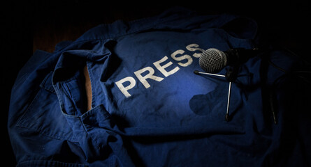 Media Journalism Global Daily News Content Concept. Blue journalist (press) vest in dark with backlight and fog. Media microphone on journalist vest.