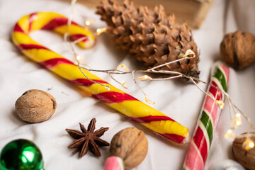 The atmosphere of Christmas and New Year. Colored caramel candies, fir cone, walnuts and garland on white background