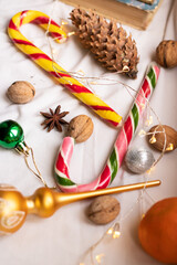 The atmosphere of Christmas and New Year. Big spruce cone, colored caramel paosokhs, Christmas balls and walnuts on a light background