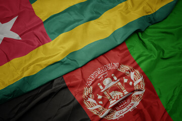 waving colorful flag of afghanistan and national flag of togo. macro