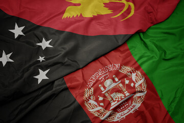 waving colorful flag of afghanistan and national flag of Papua New Guinea . macro