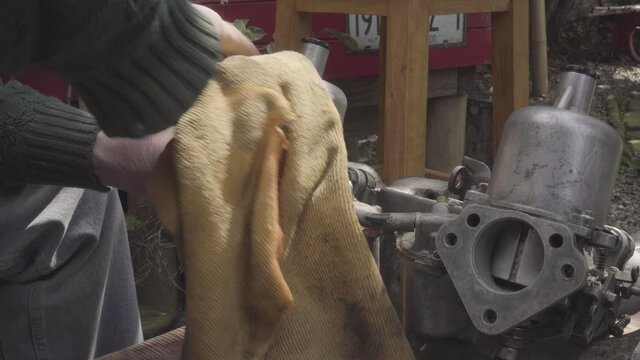 old man's hand restoring SU carburettor for Volvo 122s with multiple intake, year 62