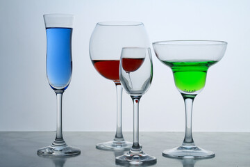 Four clear crystal glasses of different shape located at the empty background. Beautiful cocktail set at the bar.