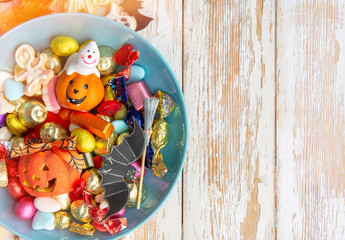 Halloween Jack o Lantern candy bowl with candy and halloween cookies Trick or Treat on blue background