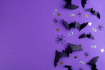 Halloween frame template with black paper bats and plastic spooky eyes on a violet color background.